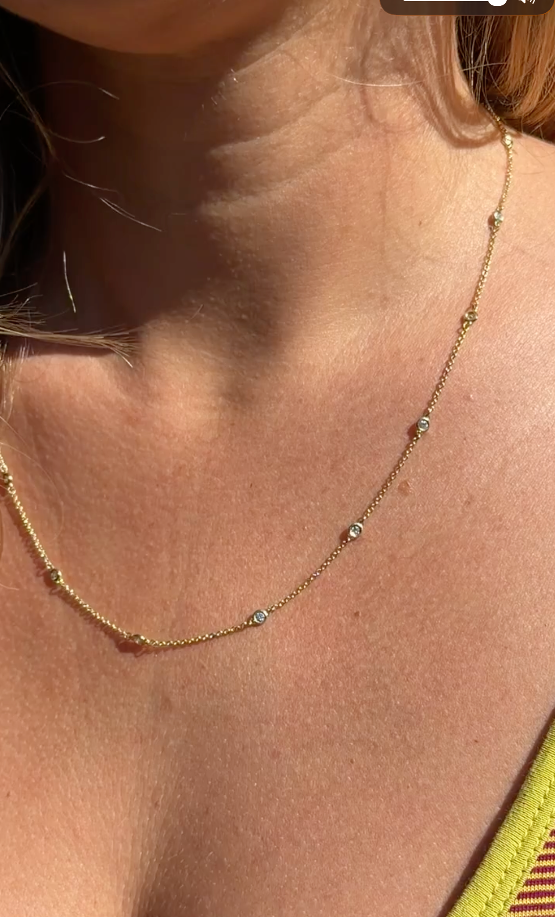 An 18k gold trace chain necklace with a bezel-set round brilliant cut diamond pendant.